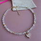 Necklace with a heart-shaped charm on a pink surface