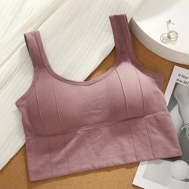 Pink ribbed sports bra on a wooden surface with a magazine and jewelry in the background