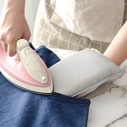 Person ironing a piece of fabric with a pink and white iron on a marble surface.