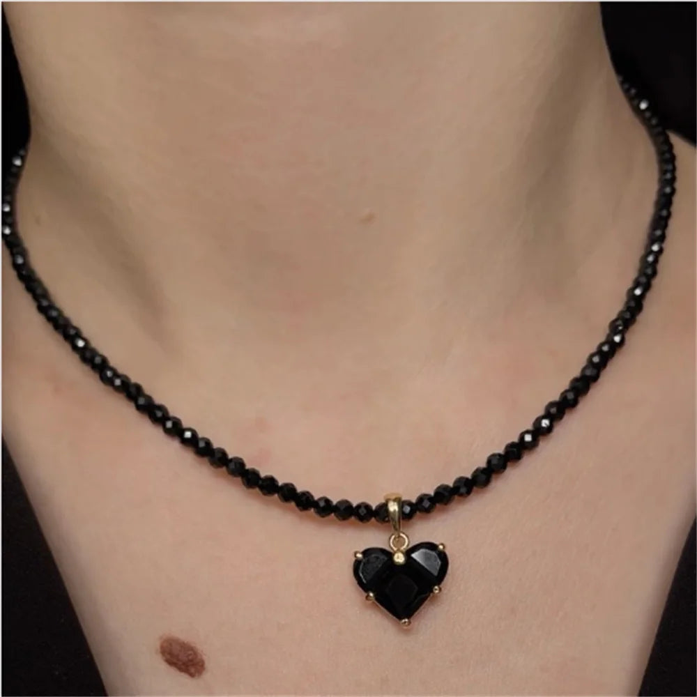 Black beaded necklace with a heart-shaped pendant on a person's neck