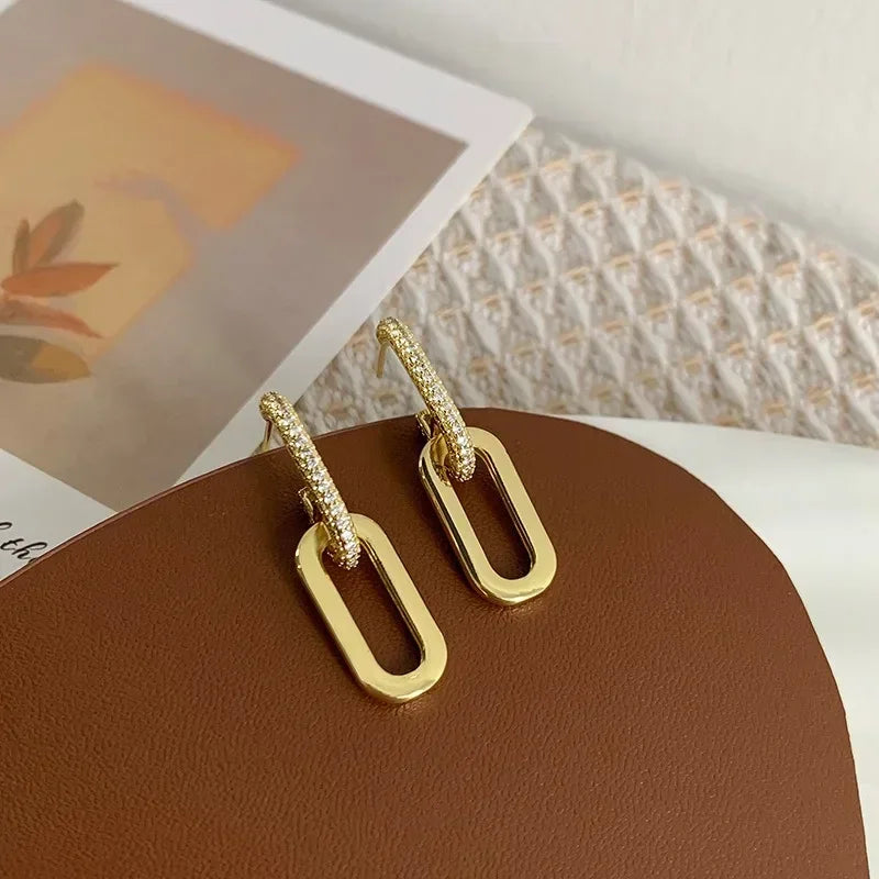 Gold hoop earrings on a brown surface with a blurred background