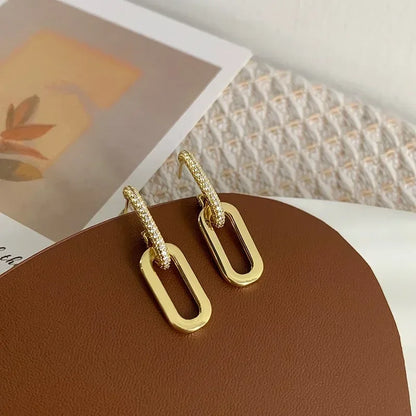 Gold hoop earrings on a brown surface with a blurred background