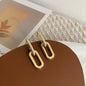 Gold hoop earrings on a brown surface with a blurred background